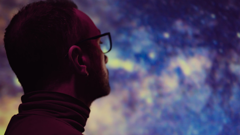 Foto. En mann ser ut over en diffus bakgrunn som kan minne om en stjernehimmel.