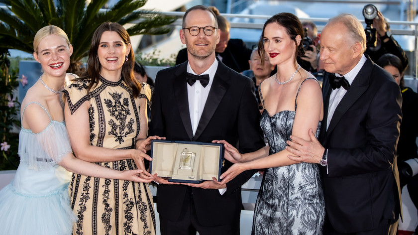 Foto. Fem personer i pentøy holder en pris i en eske foran seg.