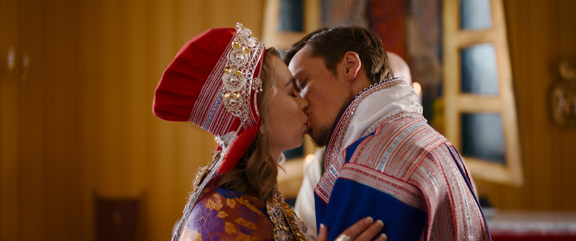 Foto. Et par ikledd samiske kofter kysser hverandre.