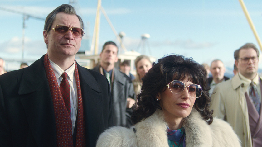 Foto. En mann og en dame står i forgrunnen av en gruppe mennesker. De har på solbriller og pent tøy.