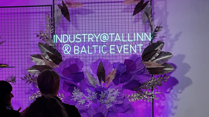 Bilde. Neonskilt på en nettingvegg dekorert med kunstige blomster.