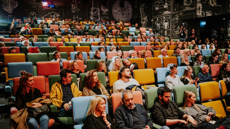 Foto. Publikum i en kinosal med fargerike seter.