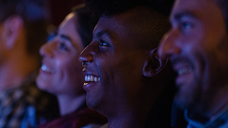 Foto. Nærbilde av flere personer som ser på film og smiler.